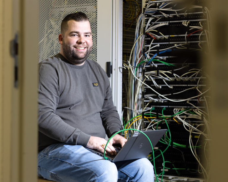 Functioneel beheerder Sander zit in technische omgeving met veel kabels.