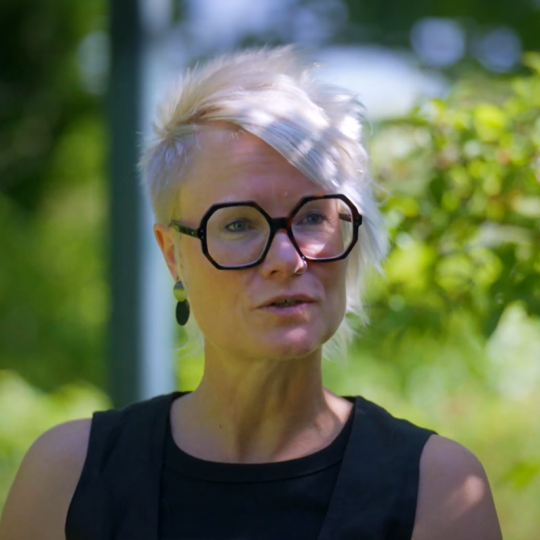 Woonbegeleider Monique zit buiten in een groene omgeving,