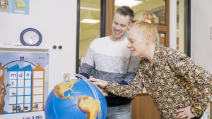 Twee onderwijzers bekijken samen een braille wereldbol.