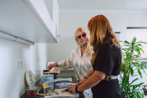 Ergotherapeut Binnen Een ergotherapeut en een slechtziende vrouw staan samenin de keuken. Ze koken met specialistische hulpmiddelen zoals een vergrootte kookwekker.