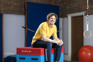 Leerkracht bewegingsonderwijs Een Leerkracht bewegingsonderwijs zit op de matten in een gymzaal