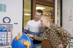 Twee leerkrachten kijken naar een speciale wereldbol met tast reliëf.