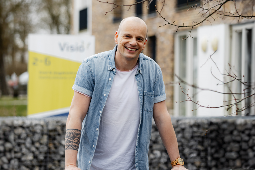 Een begeleider staat buiten in de tuin bij een Visio ,locatie.