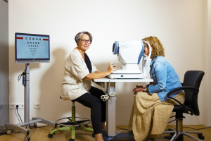 Een oogspecialist doet een onderzoek bij een client. De client kijkt door een apparaat.